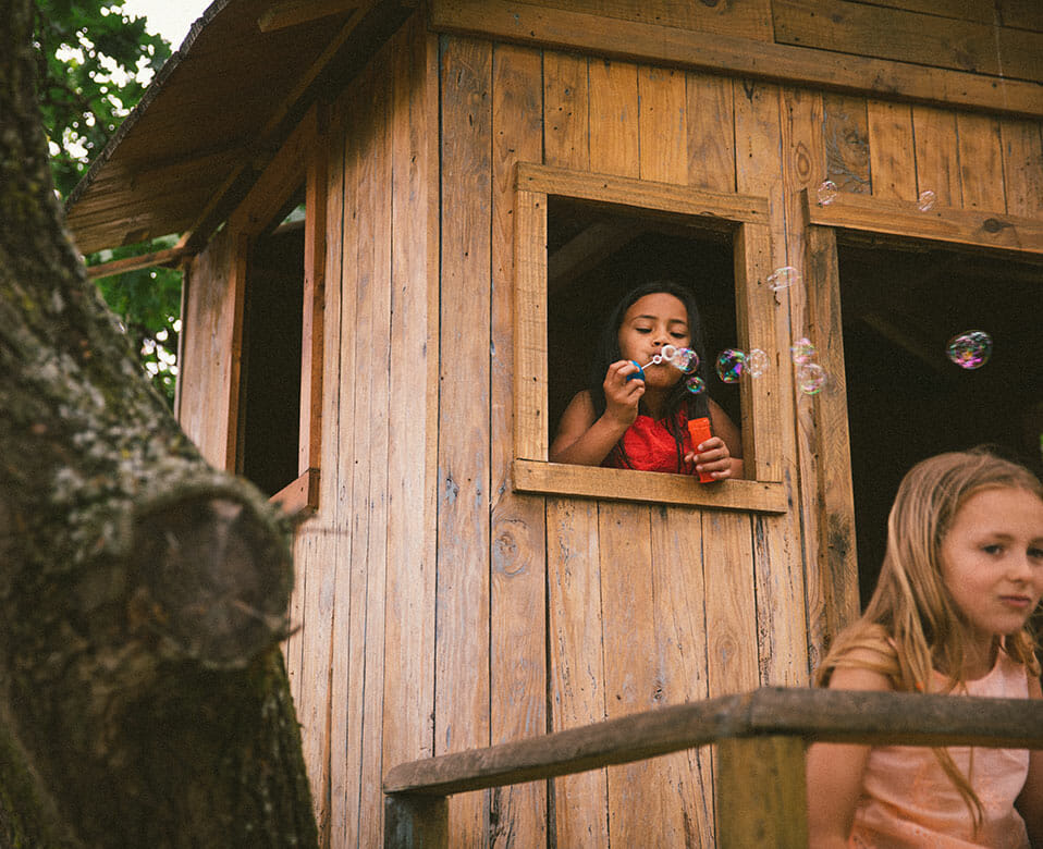 child blowing bubbles in tree house