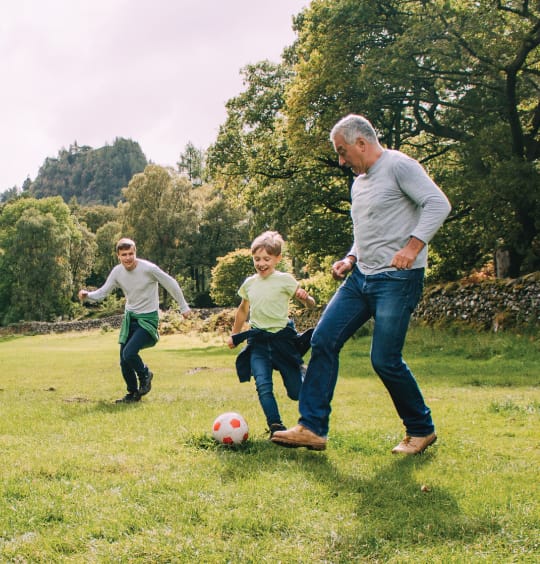 adults playing soccer with young kids