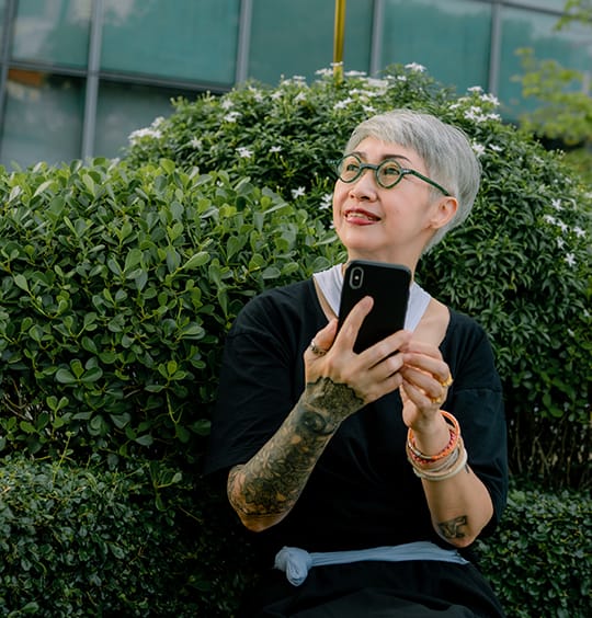 woman holding phone outside on a bench