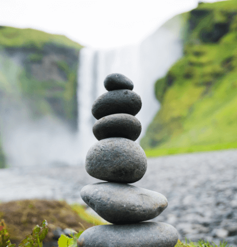 stack of rocks in front of a waterfall